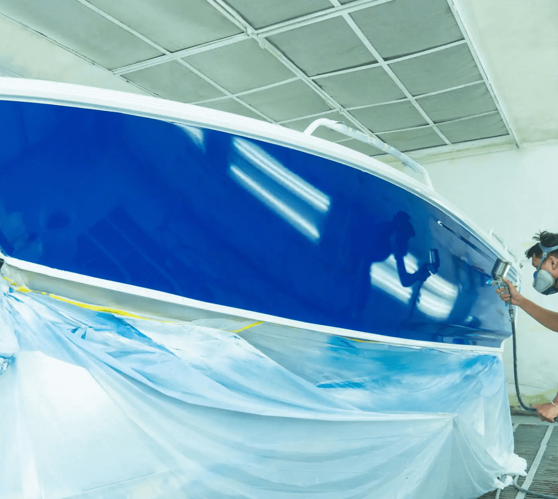 Person painting a blue boat hull